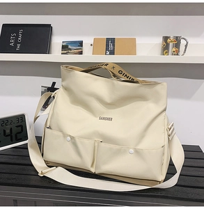 Détail du sac de voyage beige avec poches avant et sangles réglables griffées SANSHER