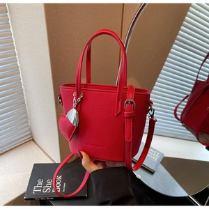 Detail of red bucket bag with lychee texture leather and a heart pendant charm