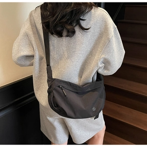 Detail view of model wearing a black crescent-shaped nylon crossbody bag with adjustable strap