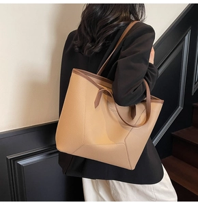 Close-up of a large tote bag in lychee texture leather with contrast brown shoulder straps