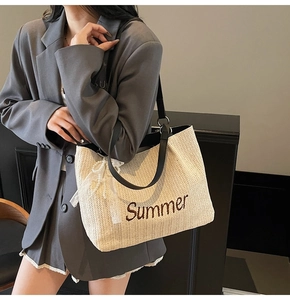 Detail of straw tote bag with Summer embroidery, leather straps and pearl bow charm