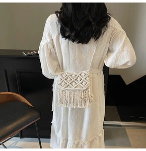 Detail of white macrame shoulder bag with fringe tassels on bohemian dress