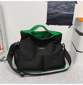 Détail du sac de voyage noir et vert avec poches avant et sangles logo SANSHER