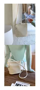 Détail du mini sac seau en cuir crème avec breloque cœur argentée et bandoulière