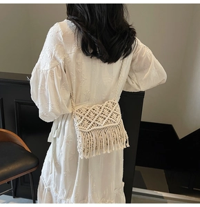 Détail du sac bandoulière en macramé beige avec de longues franges sur une robe blanche