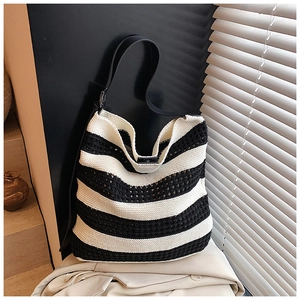 Detail of hollow knit tote bag featuring black and white stripes and leather shoulder strap