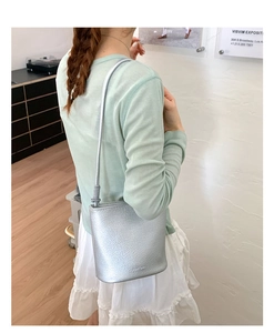 Détail d'un sac seau argenté avec texture litchi et logo embossé sur un cuir synthétique