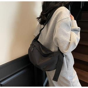 Close-up of black nylon crescent shoulder bag with adjustable strap and front pocket