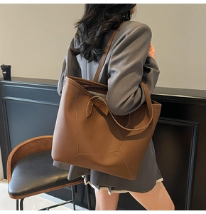 Brown litchi grain leather tote bag shown on model highlighting spacious shoulder strap fit