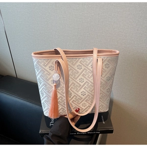 Dettaglio di una borsa tote con motivi geometrici floreali e ciondolo a nappa colorato
