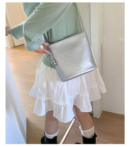 Gros plan du sac seau argenté métallisé avec texture cuir fine et logo Pantone