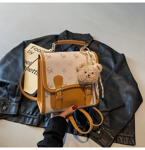 Detail des beigen Rucksacks mit Hirschprint, Retro-Metallschnallen und Bärenanhänger