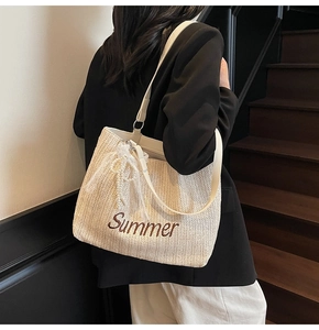 Detail of straw tote bag featuring Summer embroidery, lace ribbons, and white leather straps