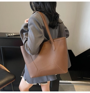 Detail of dark brown tote bag showing pebbled leather texture and geometric stitching