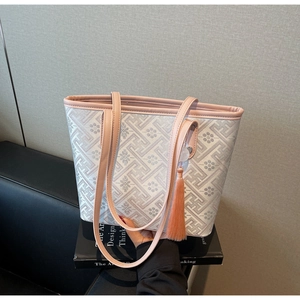 Close-up of a large capacity tote bag with grey floral pattern and pink tassel detail