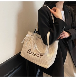 Detail of woven straw tote bag with Summer embroidery and lace pearl bow accessory