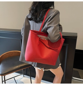 Close-up of red pebbled leather tote bag with geometric stitching on female model