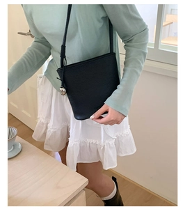 Détail du sac seau en cuir grainé noir avec charme en métal argenté en forme de galet