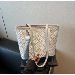 Detail of jacquard tote bag with geometric patterns, tassel pendant on a design book