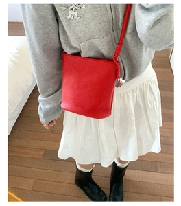 Gros plan d'un sac seau en cuir grainé rouge avec logo embossé et détail de nœud
