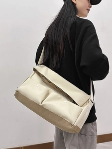 Grand sac messager en toile beige et kaki avec deux poches à boucle porté par un modèle