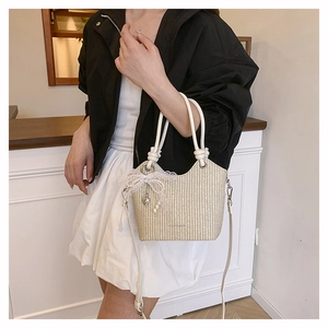 Sac seau tressé beige avec nœud en dentelle et pendentif cœur sur le mannequin