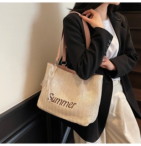 Close-up of beige straw tote with Summer embroidery, pink handles and pearl charm detail