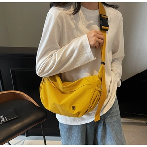 Adjustable yellow crescent crossbody bag with pleated nylon fabric and round brand logo