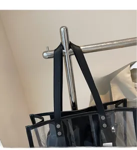 Detail of transparent tote bag featuring reinforced black leather handles and metal rivets