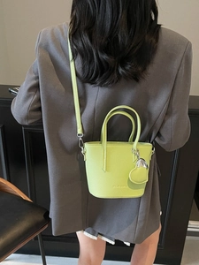 Fluorescent green bucket bag in pebble leather with heart pendant and crossbody strap
