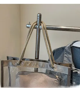 Close-up of transparent PVC tote bag featuring woven straps and matching inner pouch
