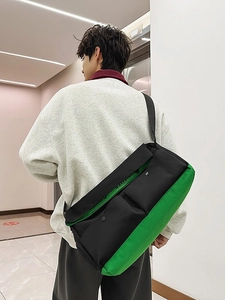 Sac bandoulière noir et vert néon porté par un mannequin dans un décor moderne