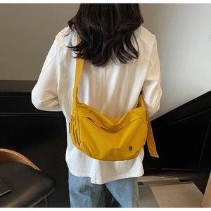 Detail of yellow nylon half-moon crossbody bag with adjustable strap and side drawstring
