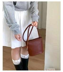 Détail d'un sac seau en cuir marron montrant sa texture fine et ses deux anses fines