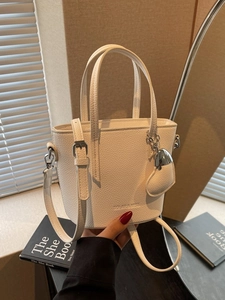 Minimalist beige bucket bag with litchi grain texture and heart-shaped metal charm