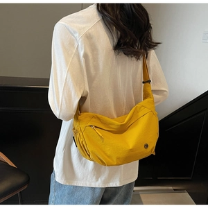 Detailed view of yellow nylon crossbody bag with ruching, metal zipper and adjustable strap