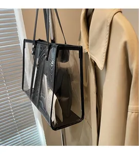 Detailed view of clear PVC tote bag with black trim hanging on a wooden hanger