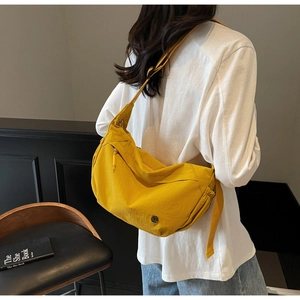 Detail of a vibrant yellow crossbody bag with adjustable strap and metallic logo accent