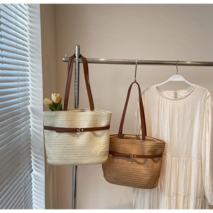 Détail de cabas en paille tissée avec anses en cuir et boucles métalliques décoratives