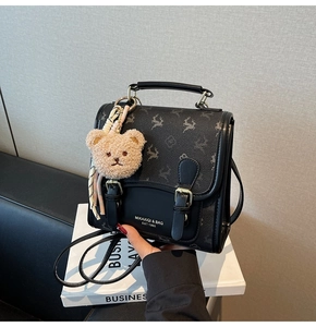 Détail du sac à dos en cuir noir avec imprimé floral, charme ours et boucles