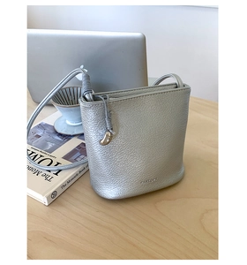Détail d'un sac seau argenté en cuir grainé sur un bureau avec un ordinateur