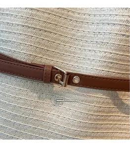 Gros plan sur un sac fourre-tout en paille tressée avec sangle en cuir brun et boucle