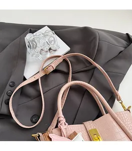 Dettaglio borsa a secchiello rosa coccodrillo con hardware oro e nastro decorativo
