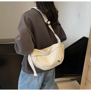 Model view of cream-white crescent crossbody bag with adjustable wide fabric strap