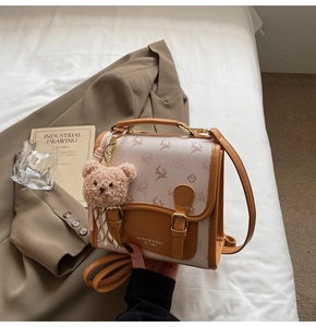 Detail der karamell-weißen Tasche mit Hirschprägung und Plüschbär-Anhänger-Dekor