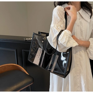 Détail d'un grand sac cabas en PVC transparent avec bordure en cuir noir porté par un mannequin