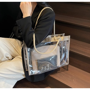 Detail of large transparent PVC tote bag with gold trim and woven rope handles