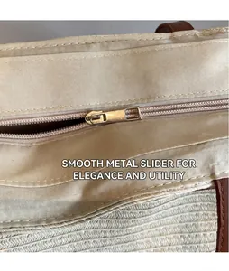 Détail de la fermeture éclair dorée et doublure en tissu du sac cabas tissé crème