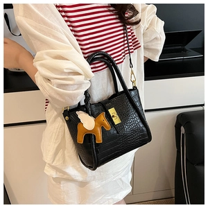 Dettaglio borsa a secchiello nera con texture coccodrillo, ciondolo a cavallo e chiusura oro