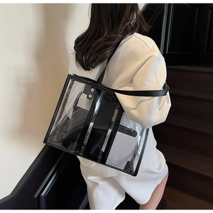 Vue latérale d'un grand sac cabas transparent en PVC avec bordures en cuir noir au bras